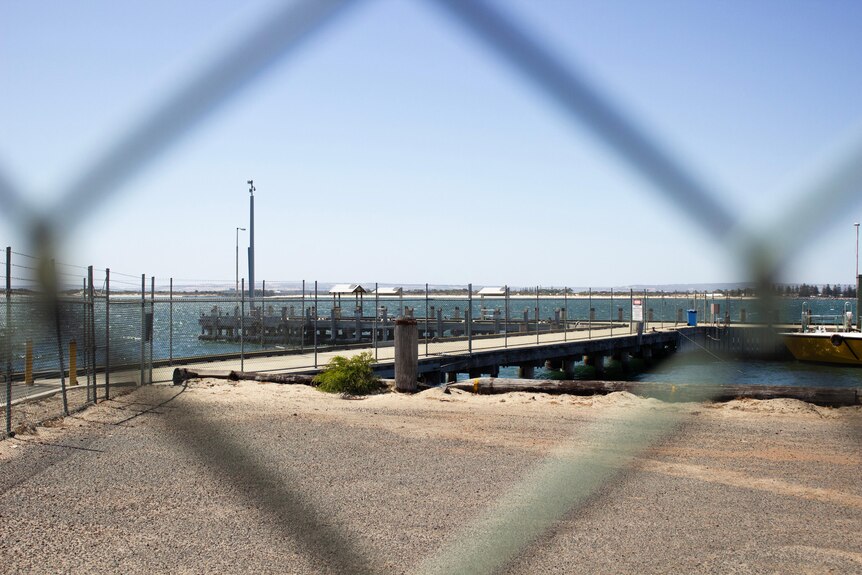 View through a fence of a jetty on the water
