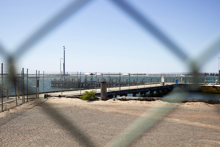 View through a fence of a jetty on the water