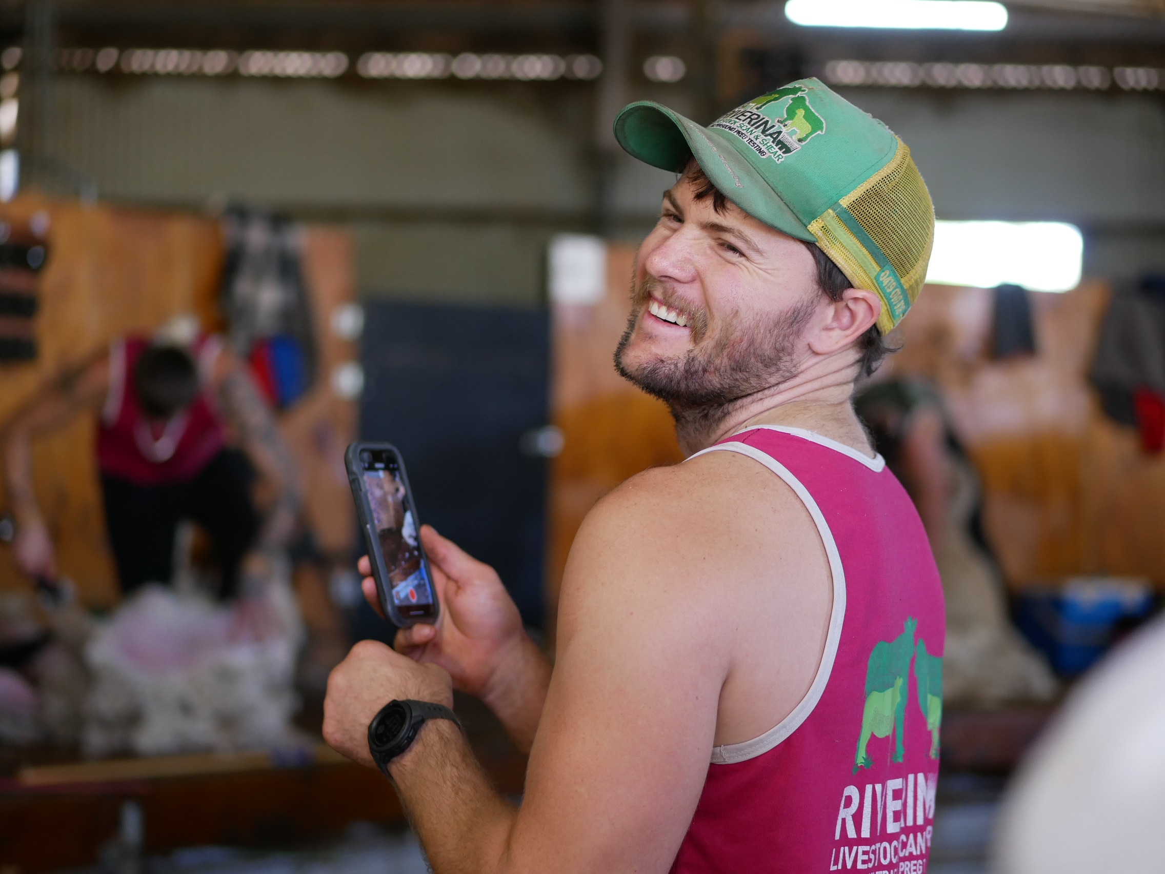 A man holding a phone filming a video and smiling. 