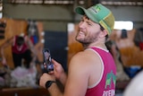 A man holding a phone filming a video and smiling. 