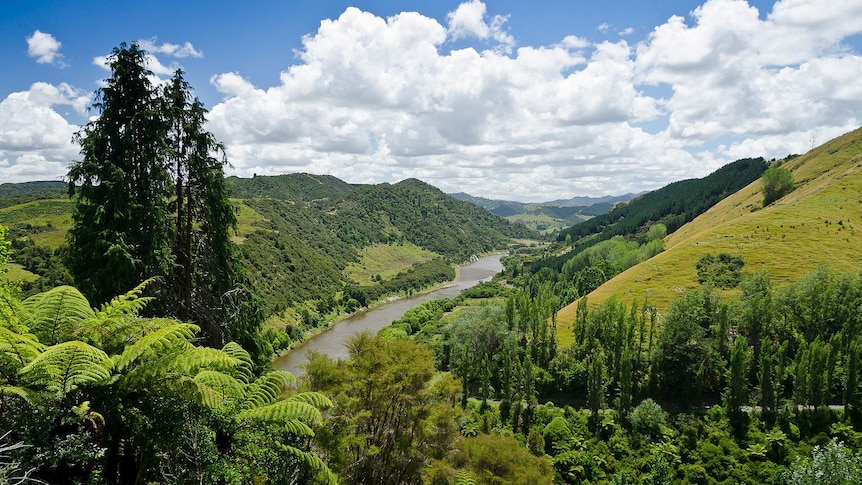 A long river cuts a valley through a forested landscape.