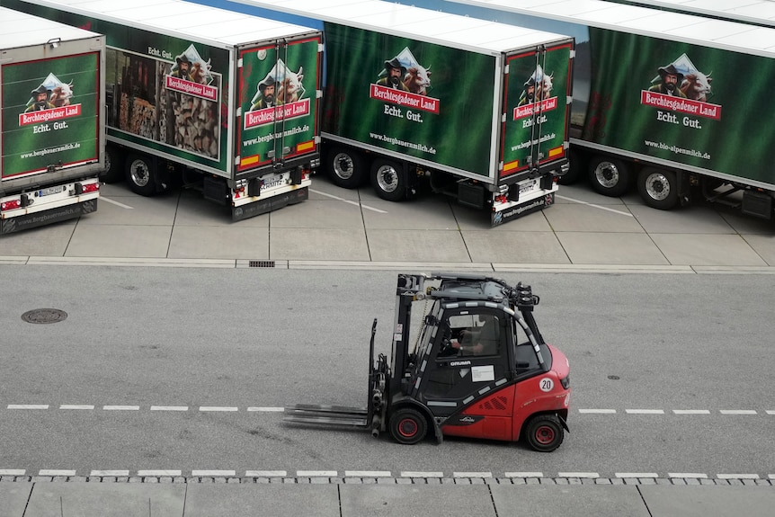 A forklift passes a row of parked trucks