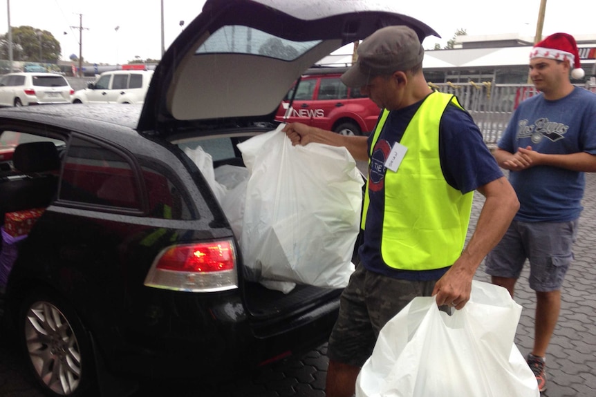 A volunteer packs gifts into the boot of his car