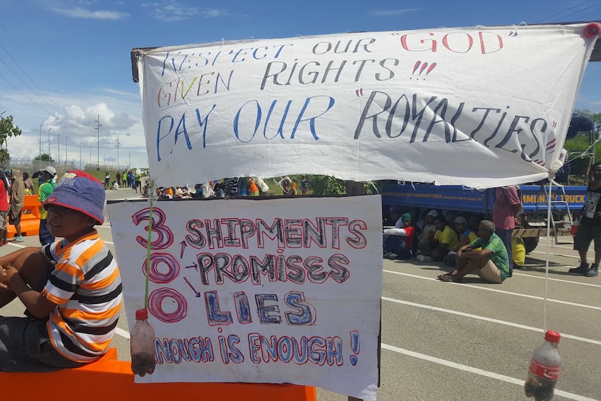 Protesters hold a "Respect our 'god' given rights!!! Pay our royalties!!!" sign at a protest.