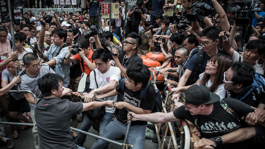 Pro-democracy protesters protect a barricade in Hong Kong from rival protesters