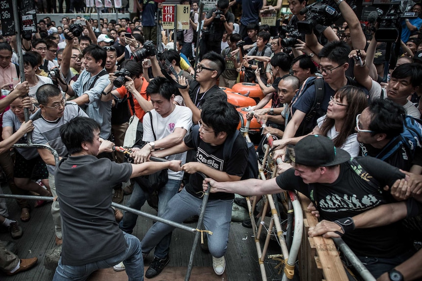Pro-democracy protesters protect a barricade in Hong Kong from rival protesters