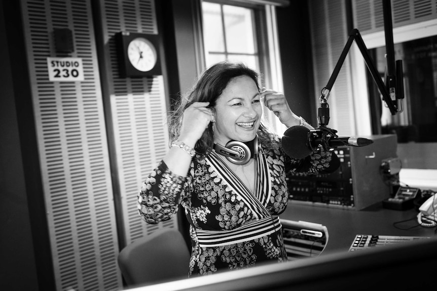 Black and white photo of Jill behind the microphone in radio studio.