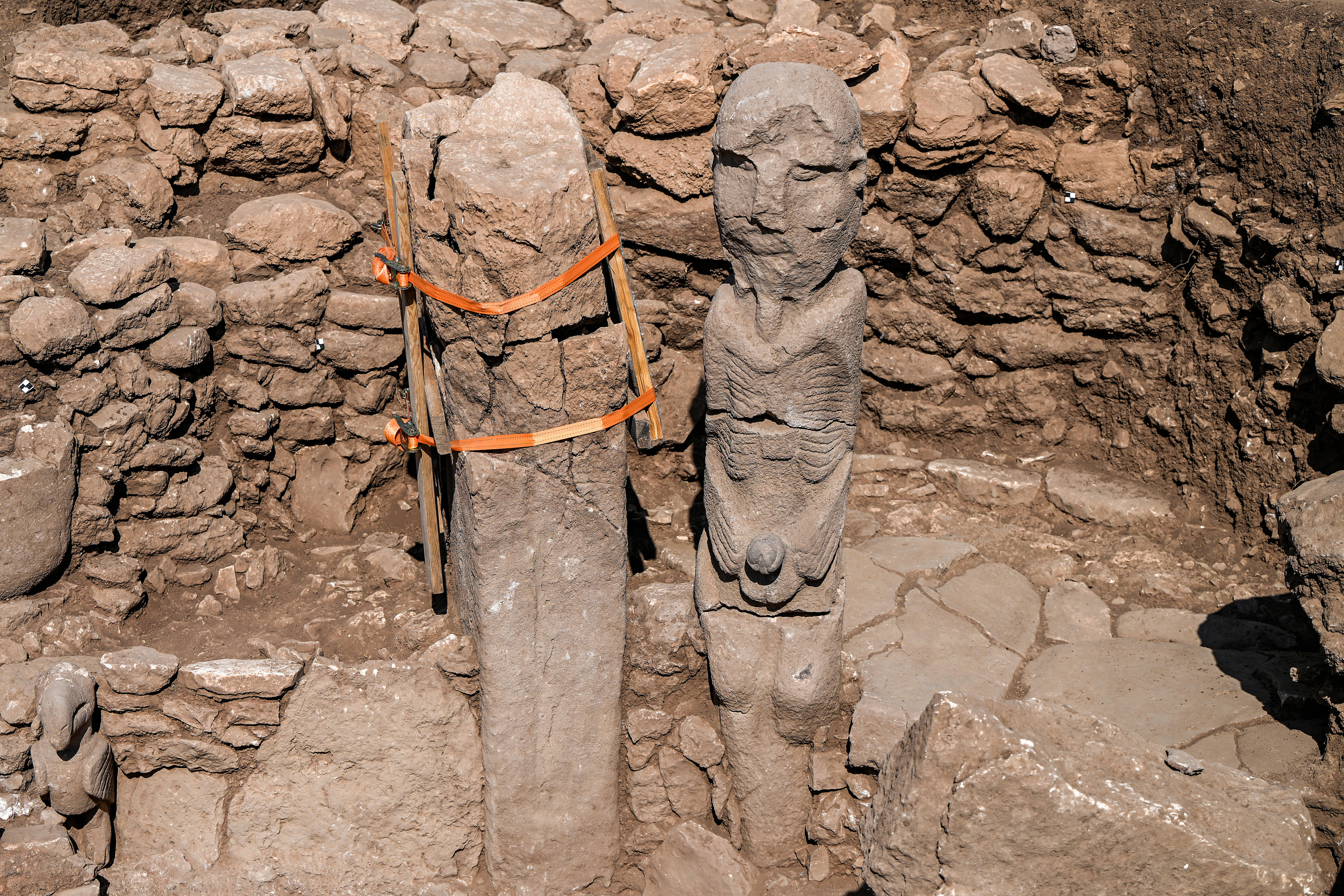 A stone statue of a seated found in found at a dig site.
