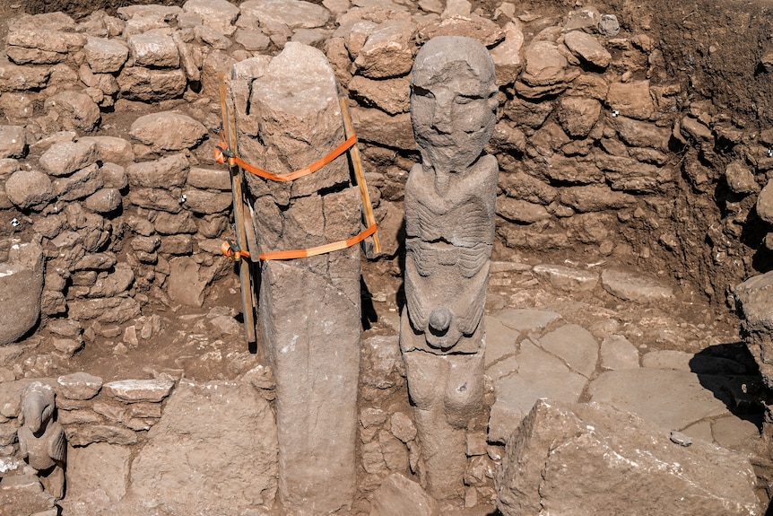 A stone statue of a seated found in found at a dig site.