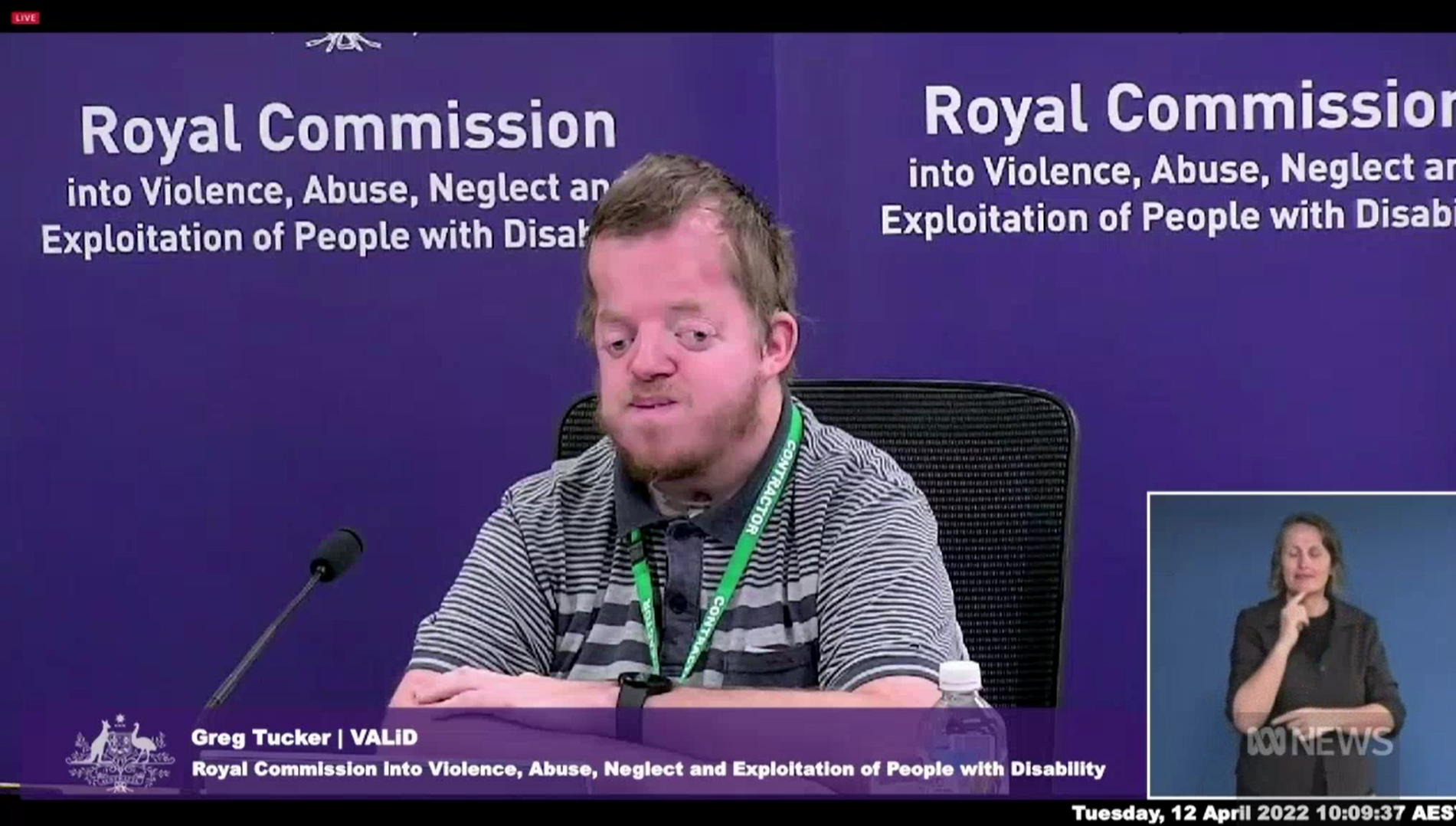 格雷格·塔克在紫色皇家委员会横幅前作证的屏幕截图。