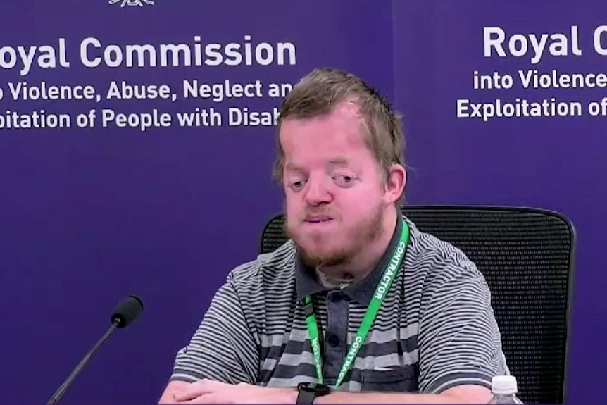 A screenshot of Greg Tucker giving evidence, in front of a purple Royal Commission banner.