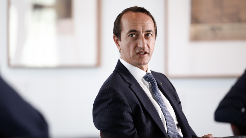 Dave Sharma sitting on a chair looking to his right mid-sentence wearing a suit and tie