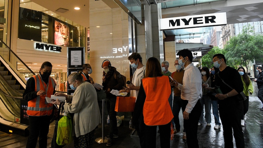 Shoppers queue outside a shopping centre in Sydney, all wearing face masks.