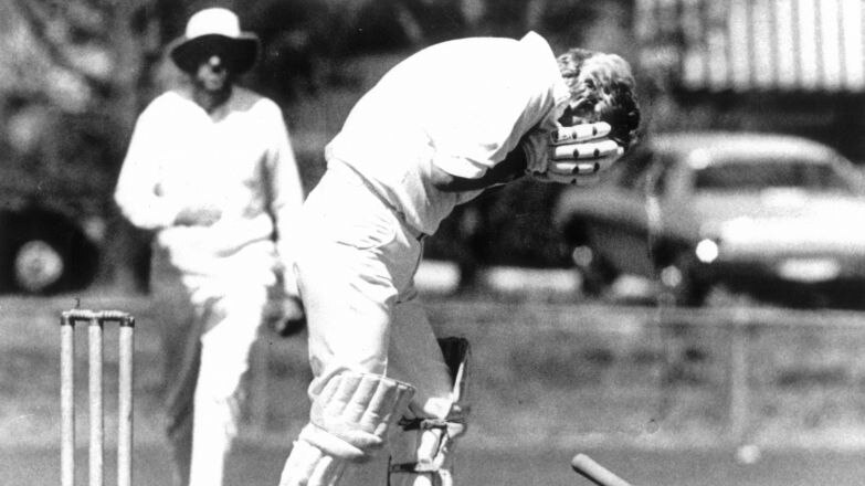 A black and white photo of Bob Hawke holding his face on the cricket pitch after being hit in the face with a ball in 1984.