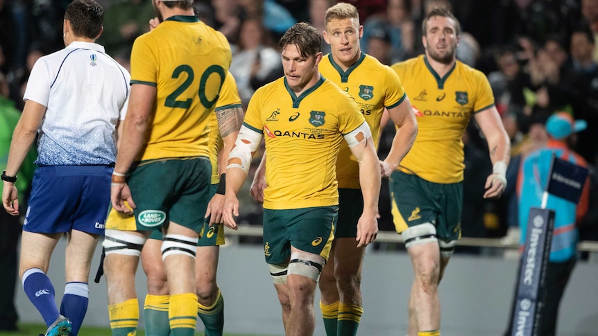 Michael Hooper walks with his head down with his teammates behind him