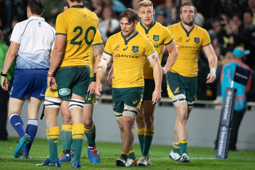 Michael Hooper walks with his head down with his teammates behind him