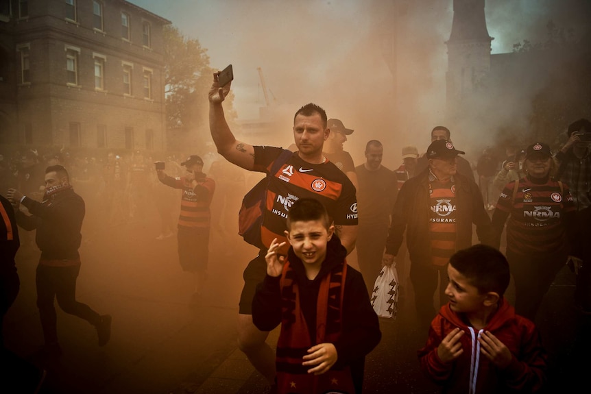 Two young boys and several men emerge from a smoky haze.