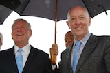 Colin Barnett shares an umbrella with Paul Miles as rain falls.