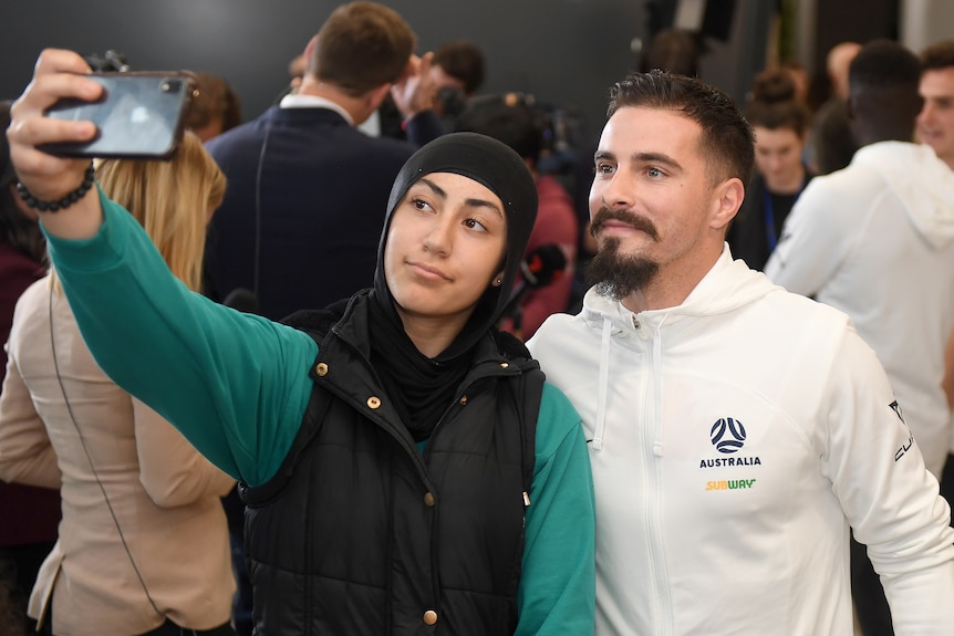 Jamie Maclaren poses for a selfie with a fan at Melbourne Airport.
