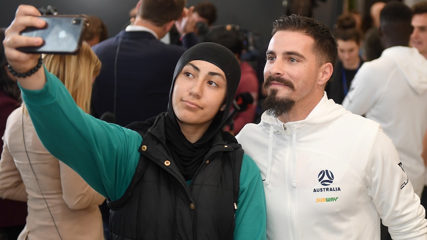 Jamie Maclaren poses for a selfie with a fan at Melbourne Airport.