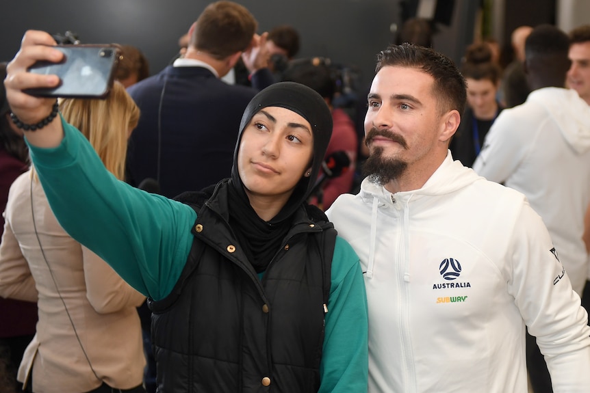 Jamie Maclaren pose pour un selfie avec un fan à l'aéroport de Melbourne.