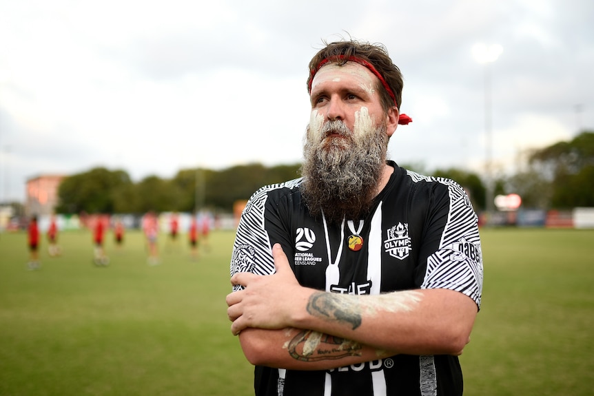 Gweagal-Dharawal man Phil Canham folds his arms and looks on at a NAIDOC week event.