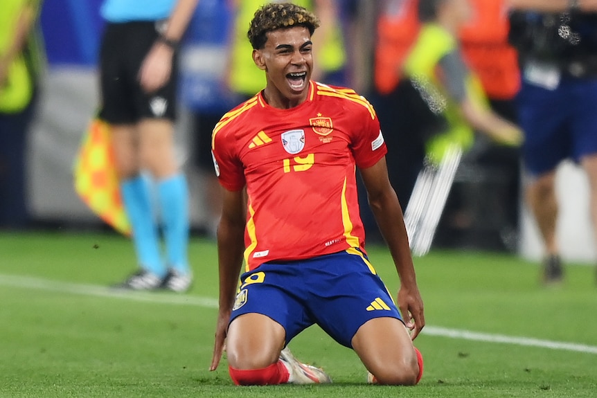 Lamine Yamal slides on his knees as he celebrates a goal for Spain against France at Euro 2024.
