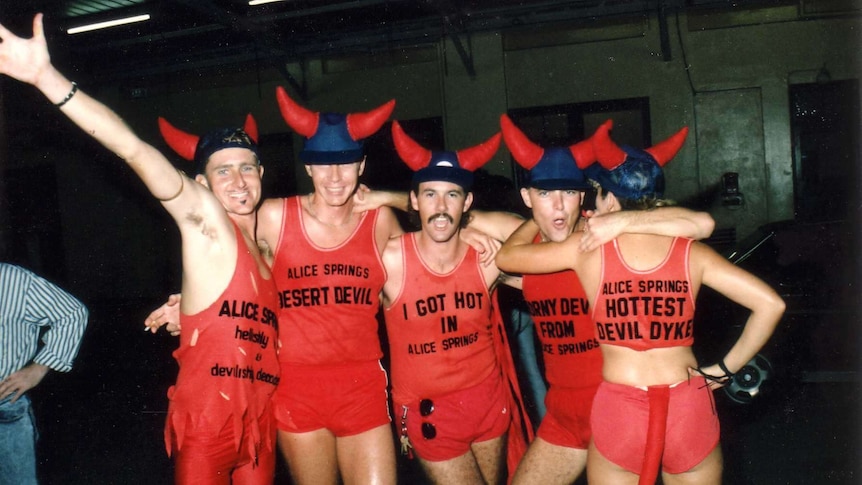 Five people stand together wearing red singlets at the 1988 Mardi Gras.
