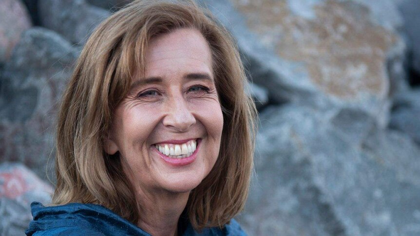 Portrait of Kathryn Heyman, smiling, against rocks