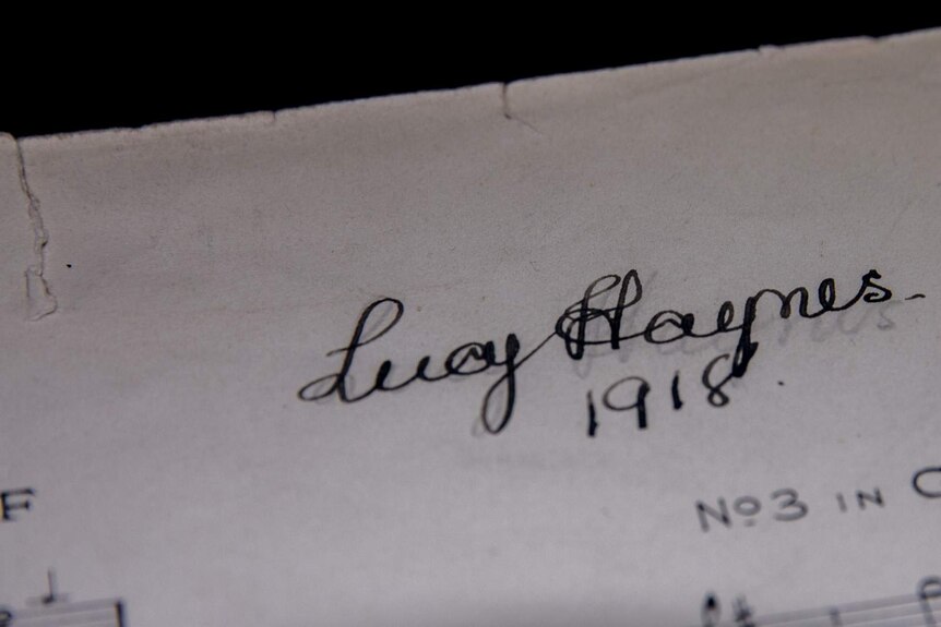 A signature of Lucy Haynes in spidery handwriting and the date 1918 on a piece of faded, torn paper