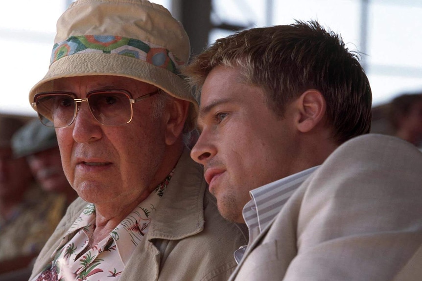 Carl Reiner wearing sunglasses and a hat sitting next to Brad Pitt