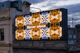 A billboard with the words "Never Alone" on the top of an old building on a cloudy dark day