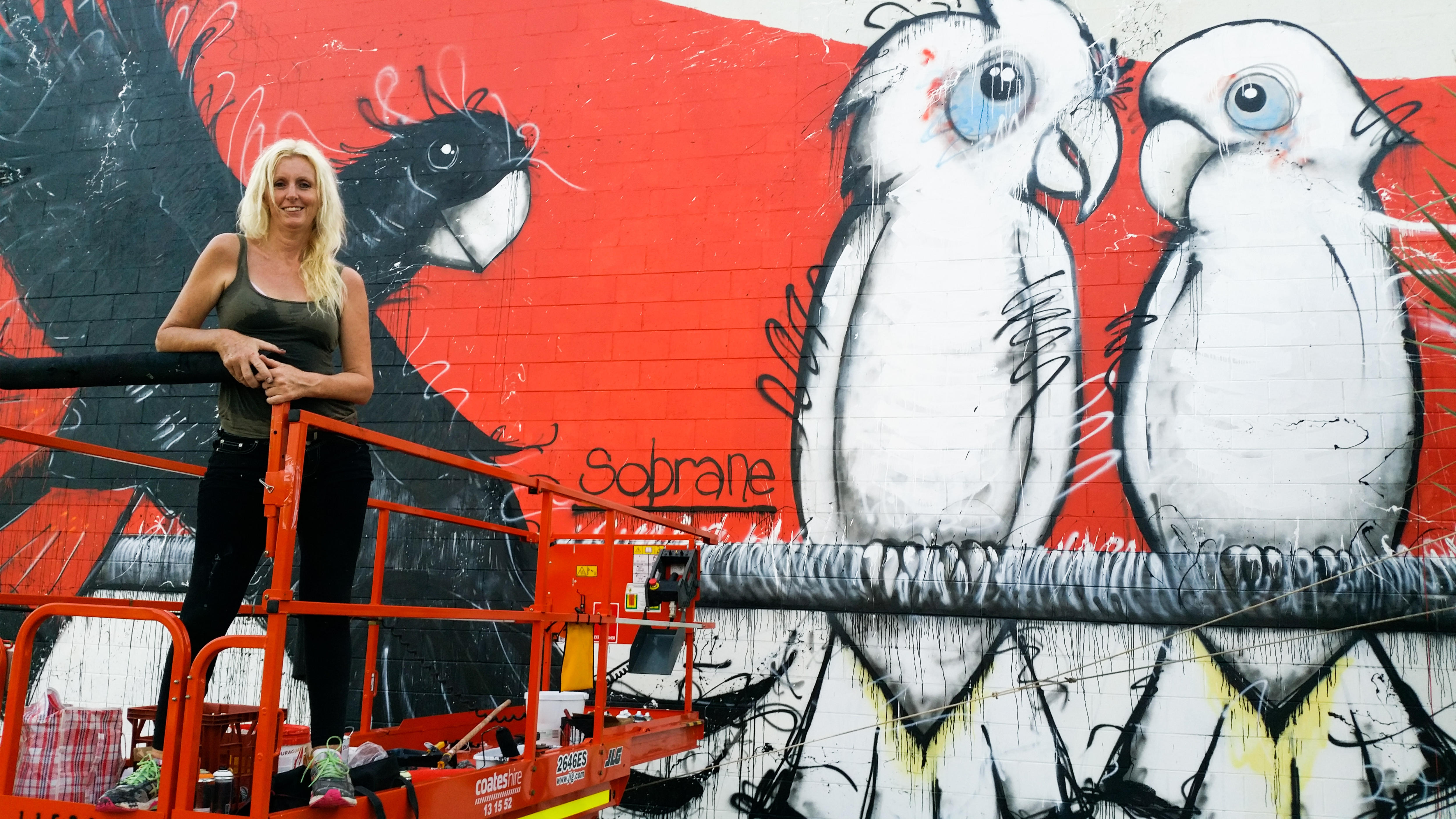 A woman in front of a colourful mural