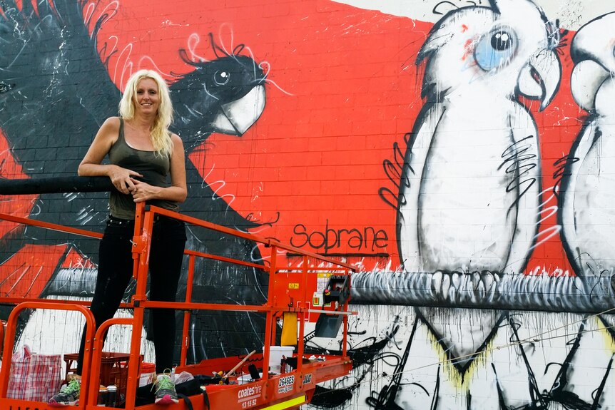 A woman in front of a colourful mural