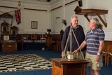 Masons Tony McKenzie and Wal Williams in the Masonic building at Forbes, NSW, with chequerboard tiles and ritual equipment.