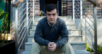 Sam Dastyari sits with his hands resting on his knees while he sits at the bottom of a set of exterior stairs