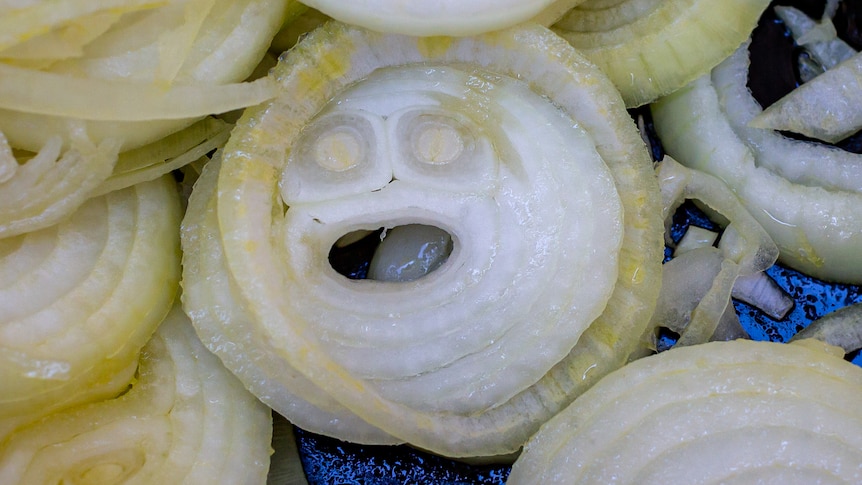 A sliced onion in a frying pan appears to have eyes and a mouth.
