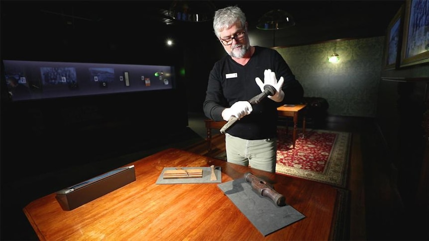 Man holds tool in musuem