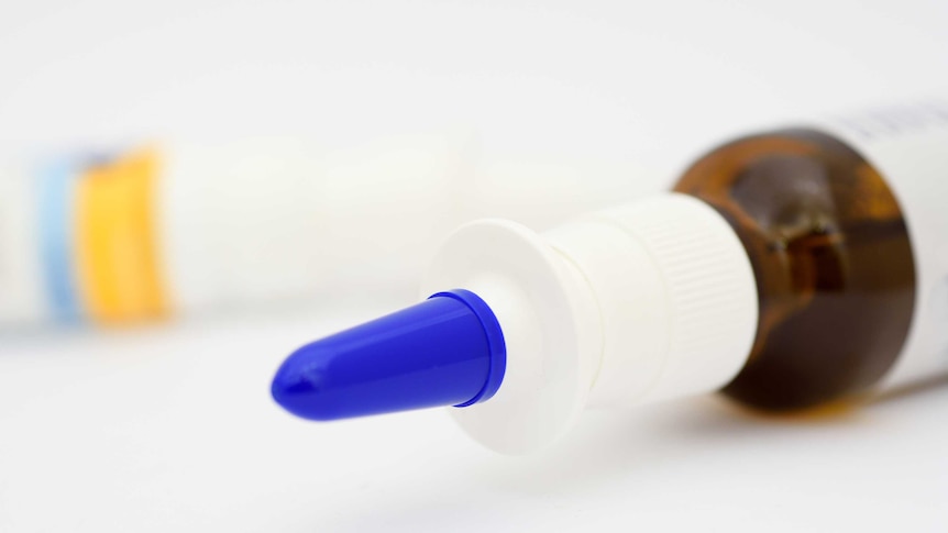 Glass nasal spray bottle with blue cap.