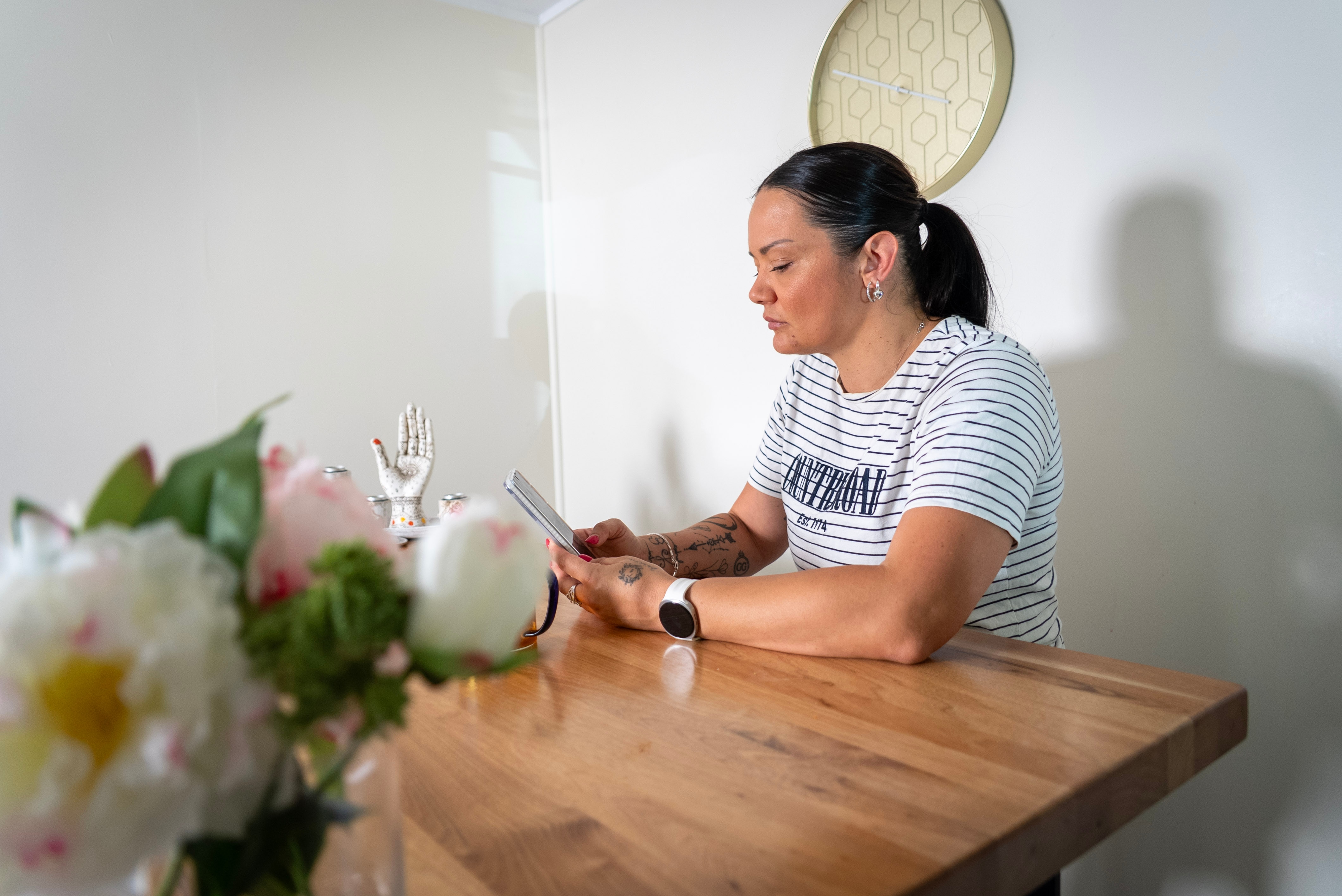 Woman sitting at a dinner room table and looking down at her phone