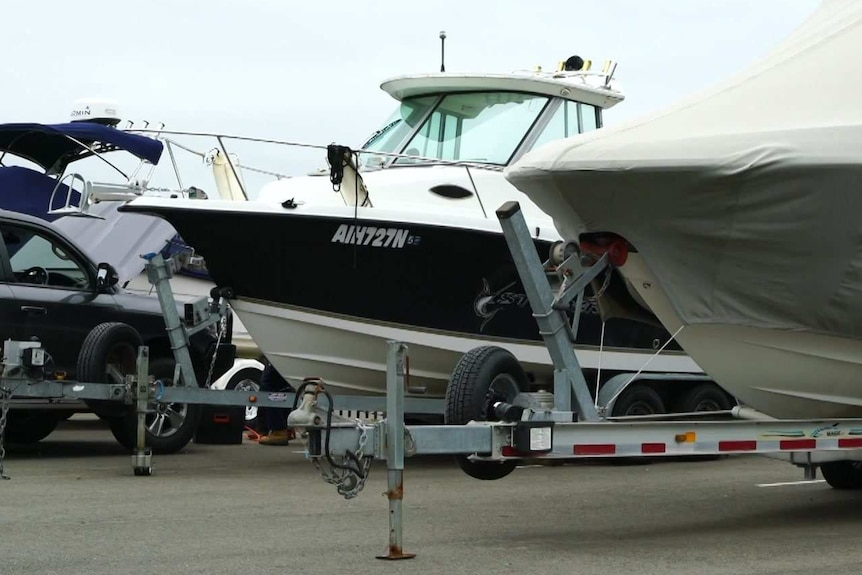 A boat on a trailer in a car park.