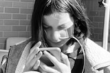 A young person with a feeding tube down their nose looks at a smartphone.