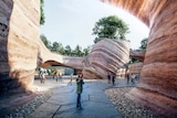 An artist's impression of the Eden Project's plan showing a person in a winter coat staring up at a red rock formation.