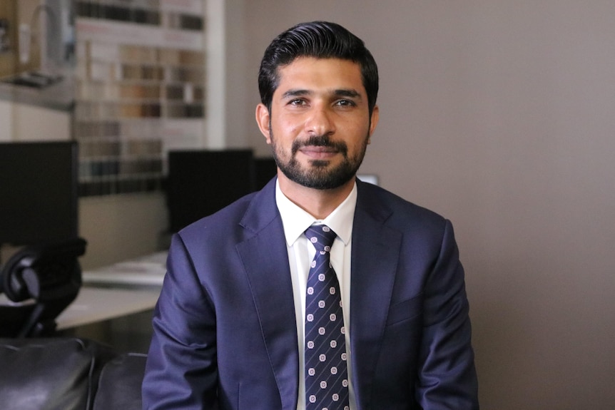 A mid shot of Ali Shah in a suit and tie looking at the camera