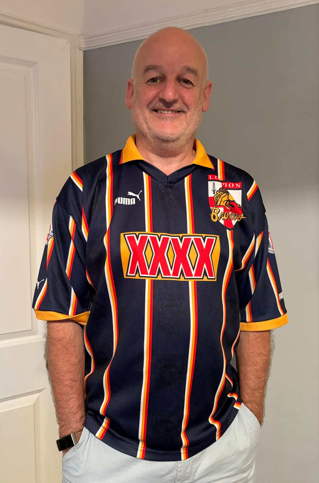 Um homem veste uma camisa da liga de rugby listrada de azul e amarelo.