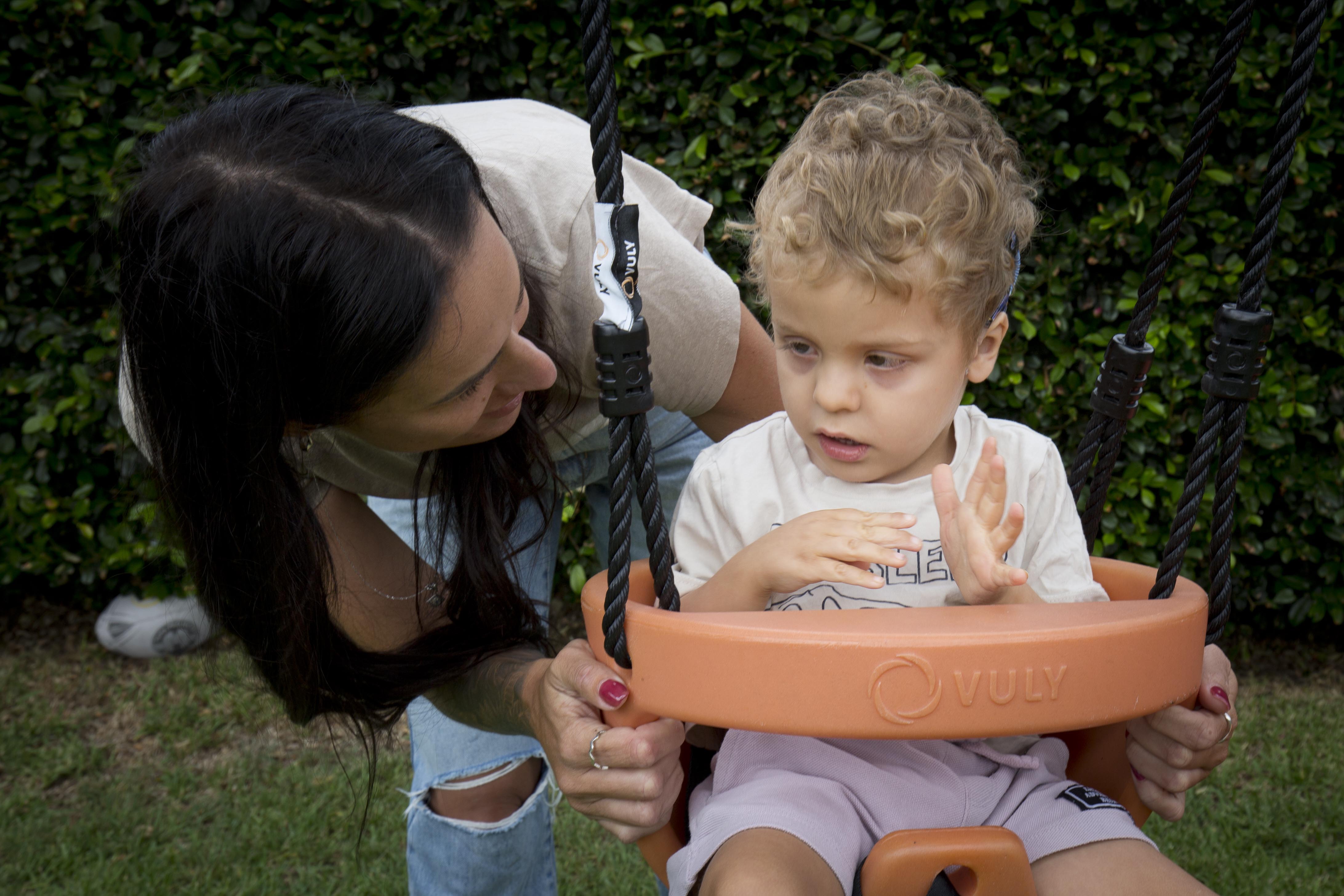 A boy in a swing tells his mum he wants more pushes using sign language.