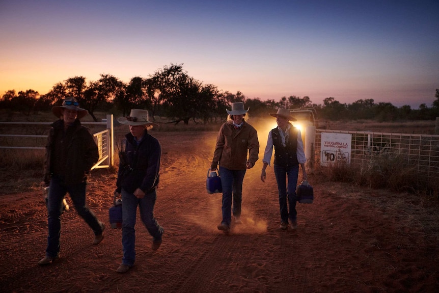 A group of station workers walk towards the Bulka cattle yards shortly before sunrise