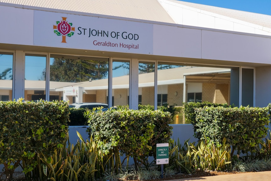 The front of St John of God Geraldton Hospital with a sign bearing the name and bushes out the front.