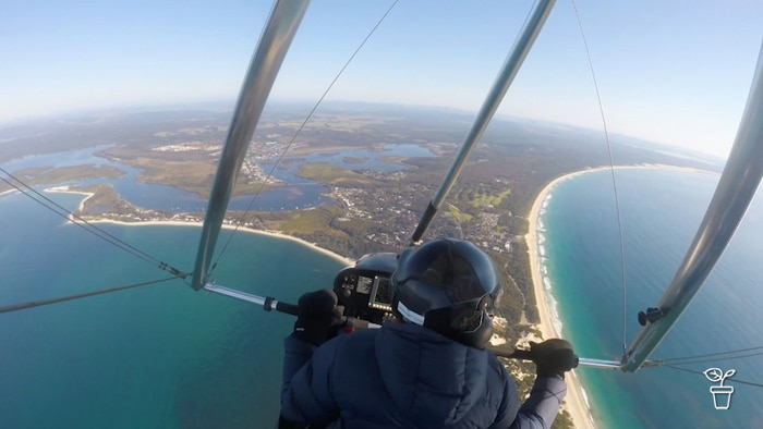Person in microlight flying over a coastline.