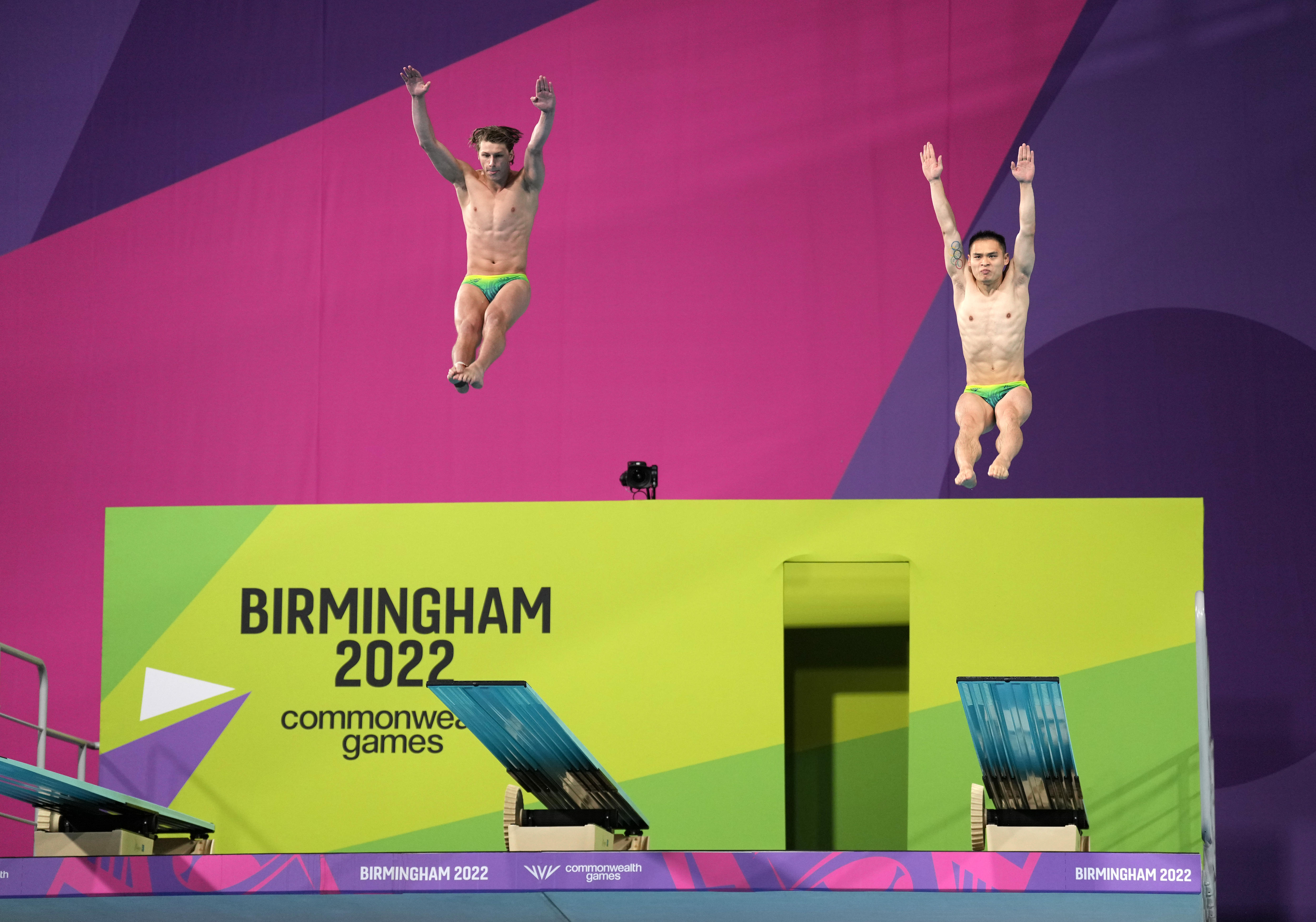Two male divers bounce off a springboard at an event